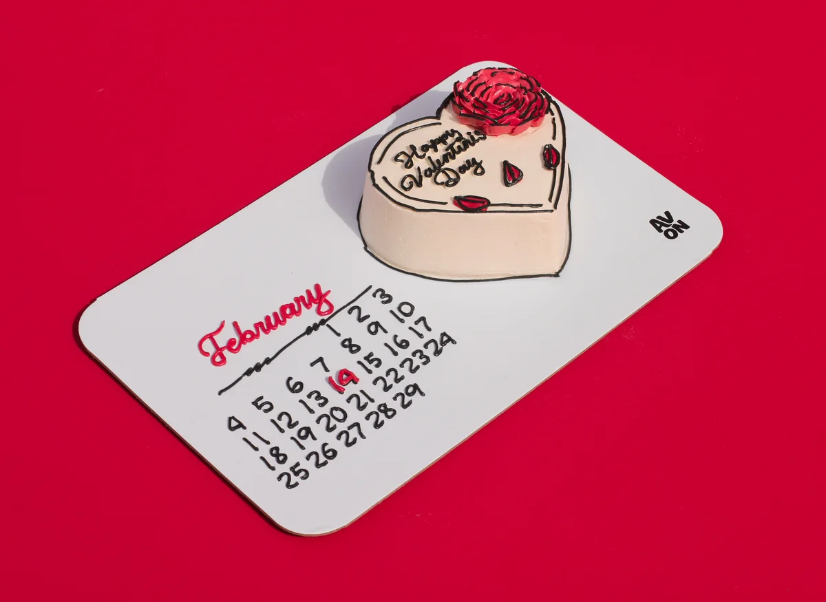 White heart cake with a rose and Happy Valentine's Day on a February calendar board