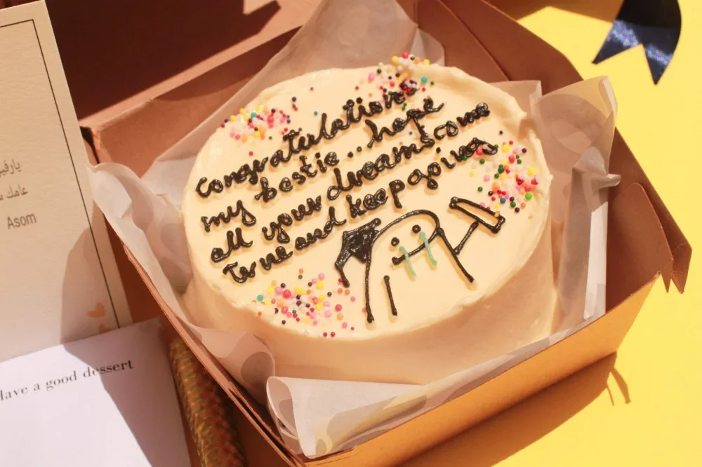 Graduation lunch box cake with a little graduate holding a diploma, a congratulations message and sprinkles