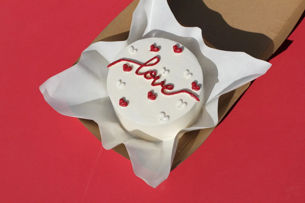 Round white Korean cake with love piped in red and small hearts
